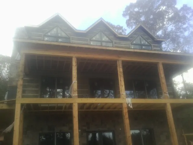 Dormers and porch framing on a large log home under construction — Roof Coating work by our crew in Paulina